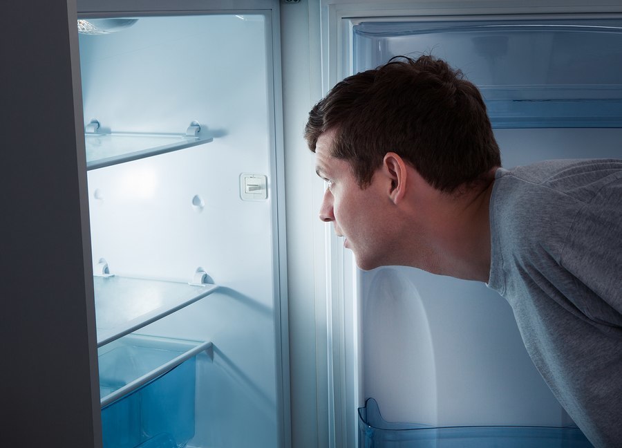 Portrait of a hungry man looking for food in refrigerator