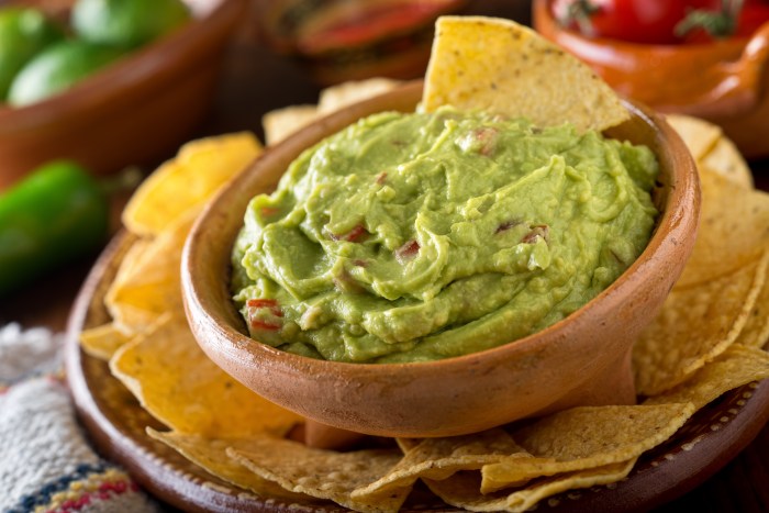 A delicious authentic mexican guacamole dip with avocado, lime, and tomato.