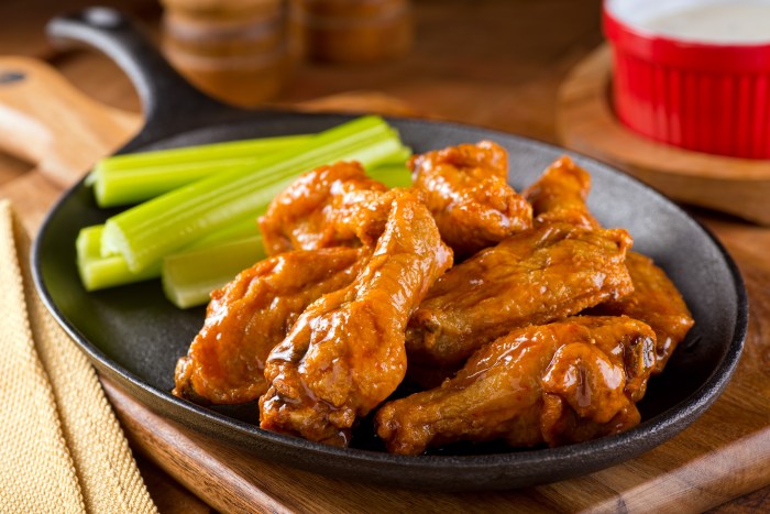 A plate of delicious Buffalo style chicken wings with celery and dipping sauce.