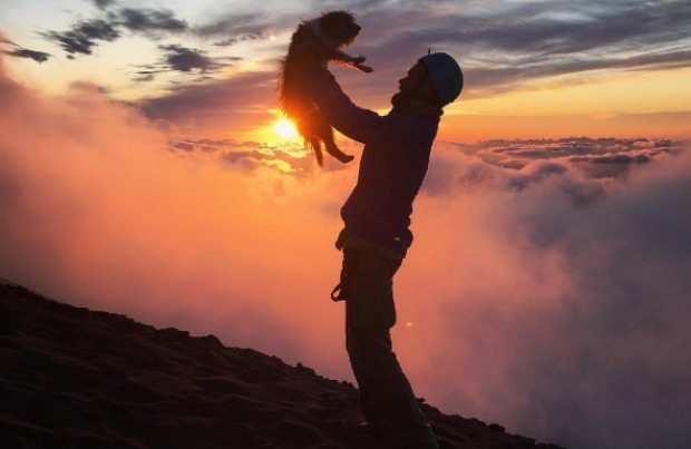 man holding dog at sunset