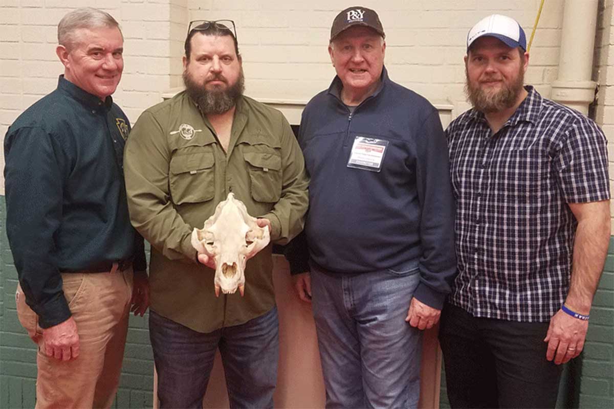 Hunter Jeff Melillo holds the world record Pope and Young Club black bear skull, surrounded by three other men