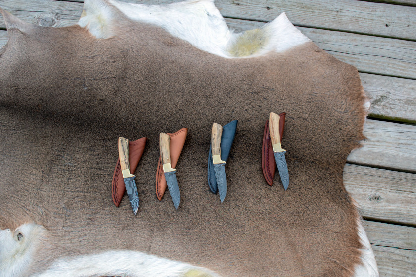 A tanned deer hide with several knives. 