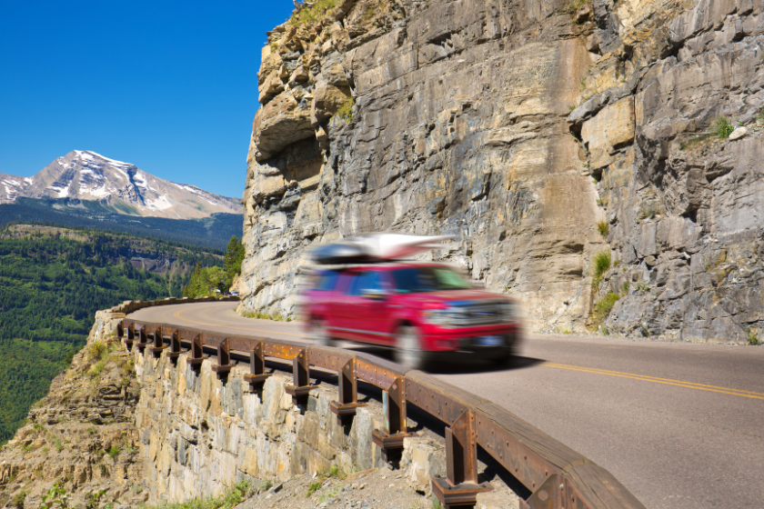 A sport utility vehicle SUV road trip vacation. Driving on the Going to the Sun Road at Glacier National Park in Montana, USA. The scenic park, highway and mountain are popular with national and international tourists.