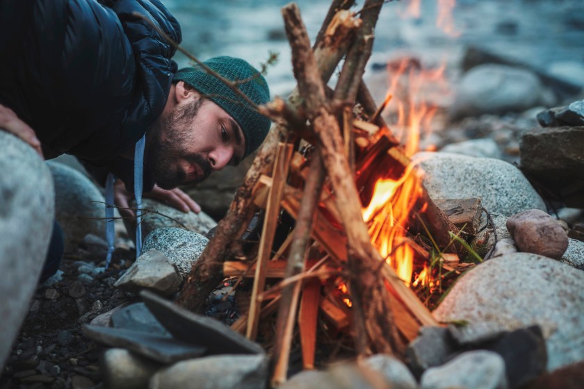 Man blowing into campfire