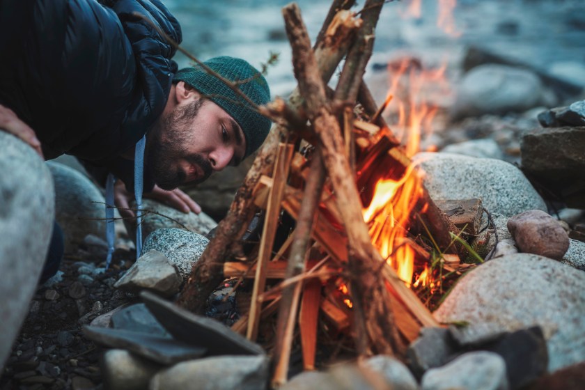 Man blowing into campfire