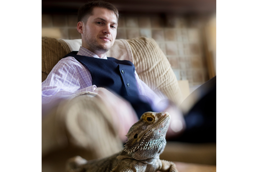 man sits and stares at his lizard