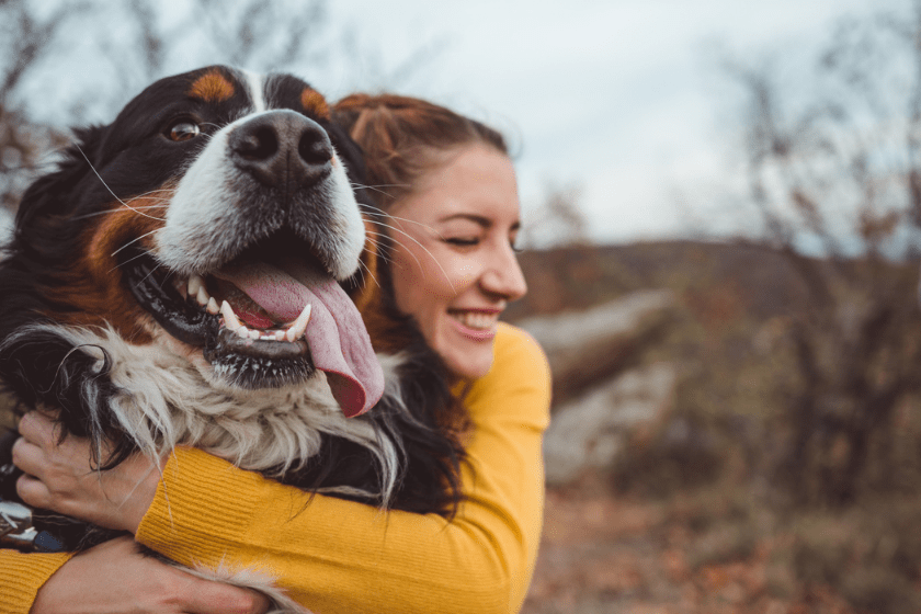 happy woman hugging dog outside