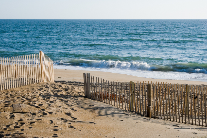 Waves breaking on the beach in morning light with an erosion control fence on the sand dunes, Outer Banks at Nags Head, North Carolina, NC, USA.