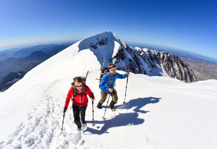 A woman and man traverse the summit ridge of Mt. St. Helens, Washington State.