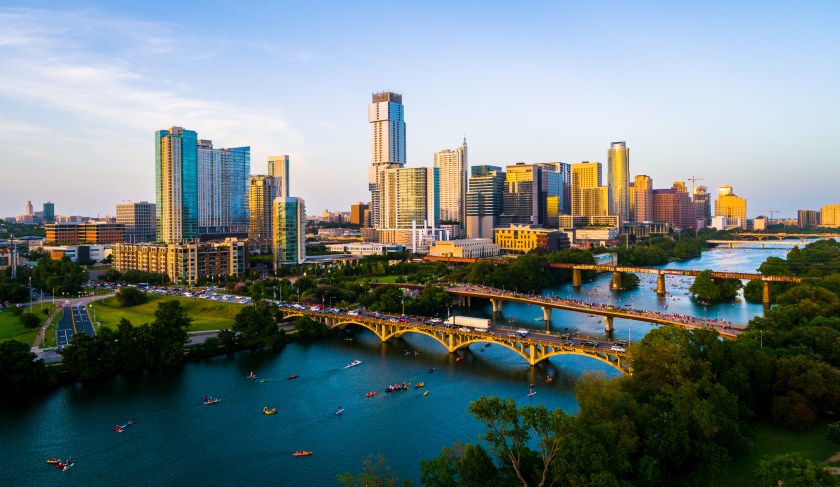 Awei drone views at golden hour Austin Texas sunset of a modern future city above green landscape cityscape above Town lake or Lady Bird Lake bridges and towers packing with kayakers