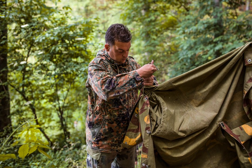 Hunter constructing tent in forest