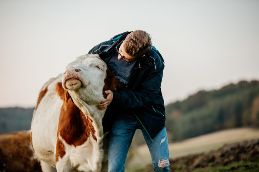 man with cute farm animal outside