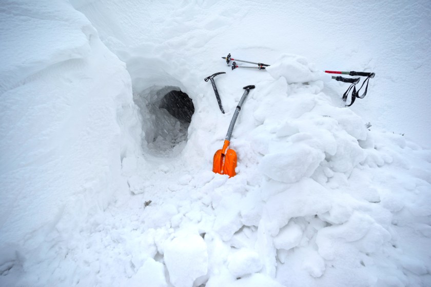The snow cave was built by a mountaineer climbing mountains for survival during extreme weather. A bright red outfit, reliable tools, confidence in the journey