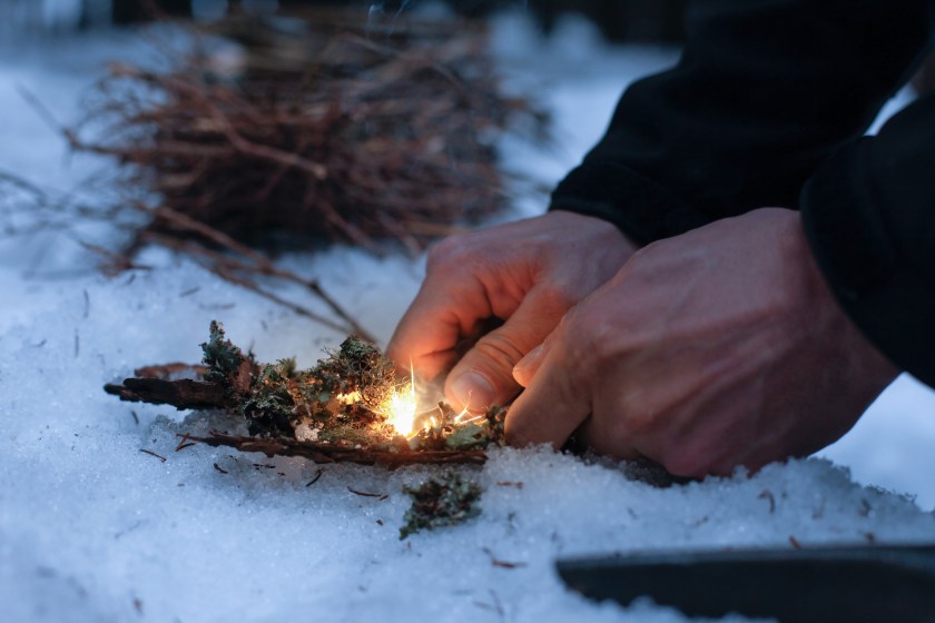 winter survival man lighting fire