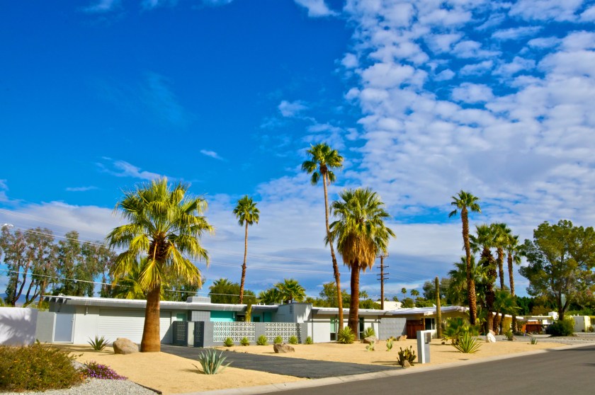 "Palm Springs, California is famous for it's many Mid-Century Modern architectural style homes. In this image a row of such homes are seen on one street with a dramatic cloudscape above them. Palm trees line the street. Coachella Valley, Riverside County, Southern California, Western USA."