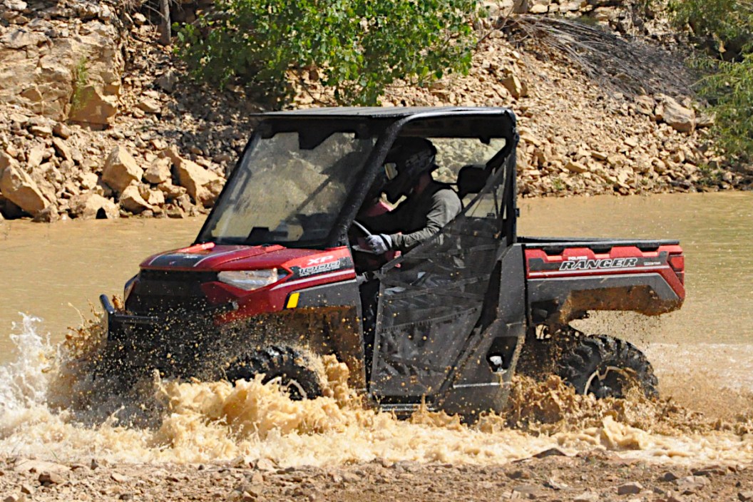 A Polaris Ranger off-road vehicle driving through a huge mud puddle.