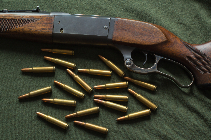 A Savage Model 99 lever-action rifle on a table with ammo.
