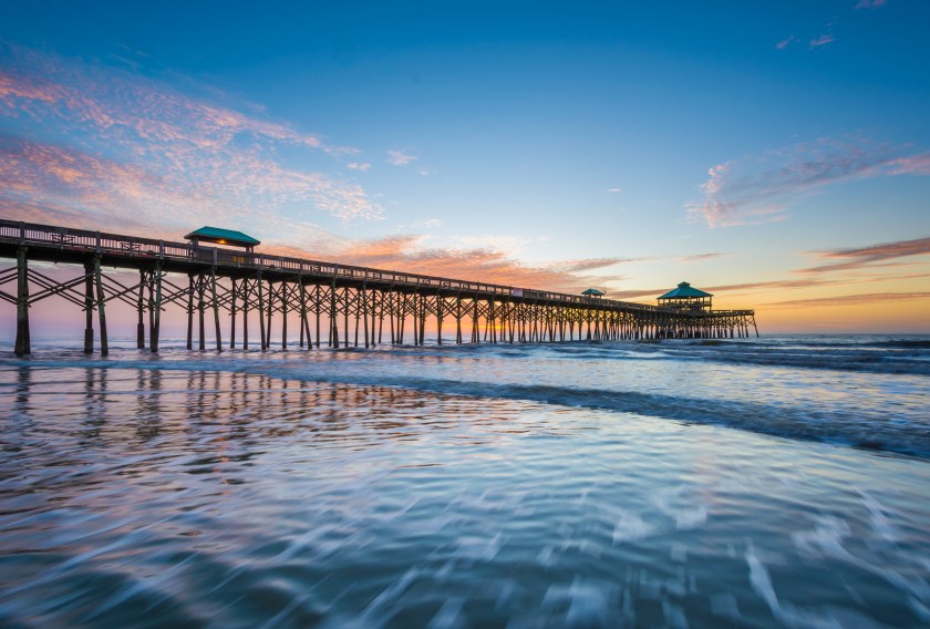 Waves in the Atlantic Ocean and the pier at sunrise, in Folly Beach, South Carolina