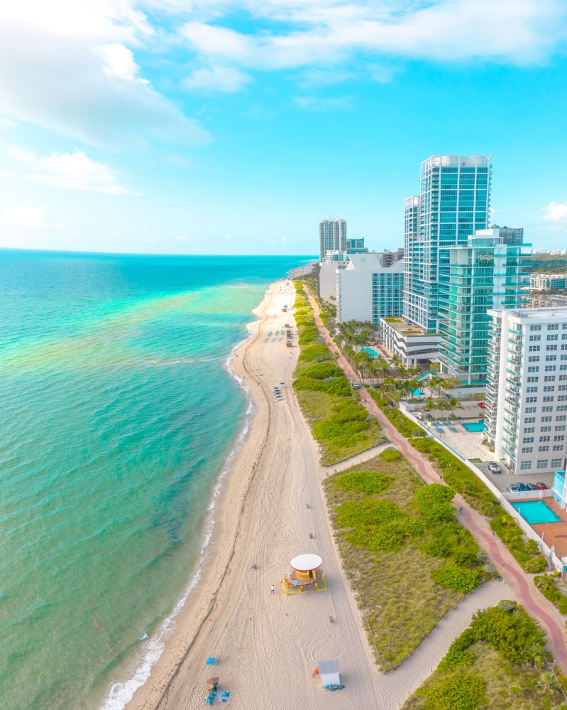 Modern waterfront architecture on display with blue ocean water and white sand