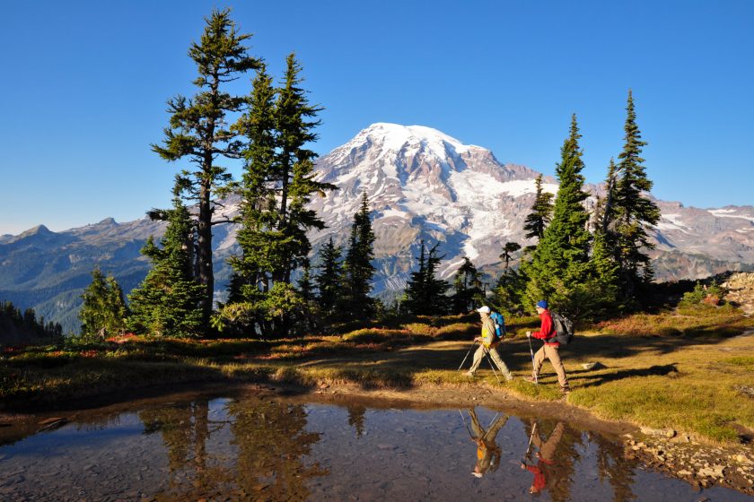 "Two hikers walk by a small pond in Mt. Rainier National Park, Washington State."