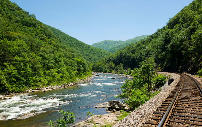 A single train track beside the Nolichucky River, curving through the Appalachian Mountains near Erwin, Tennessee.