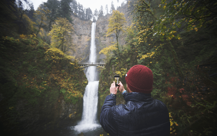 A Caucasian male 40-44 years with a red beard taking photographing the Multnomah Falls Columbia River Gorge Portland Oregon USA in the rain