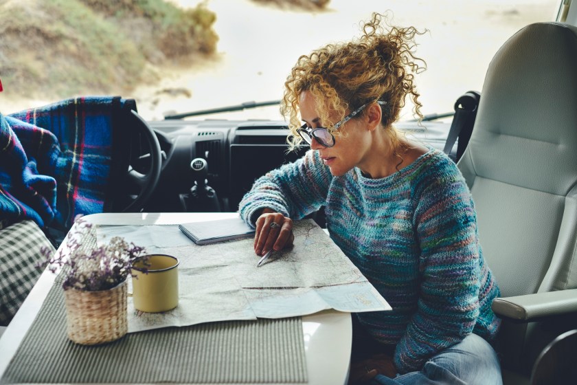 Woman planning destination on a guide paper map