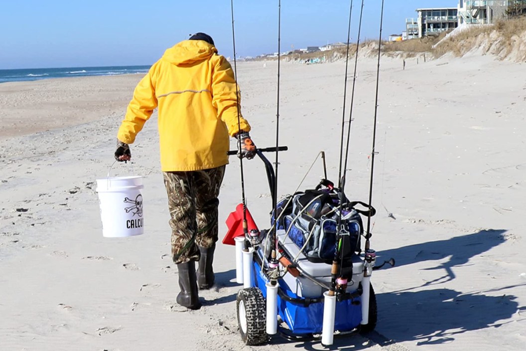 An angler pulling a beach fishing cart.