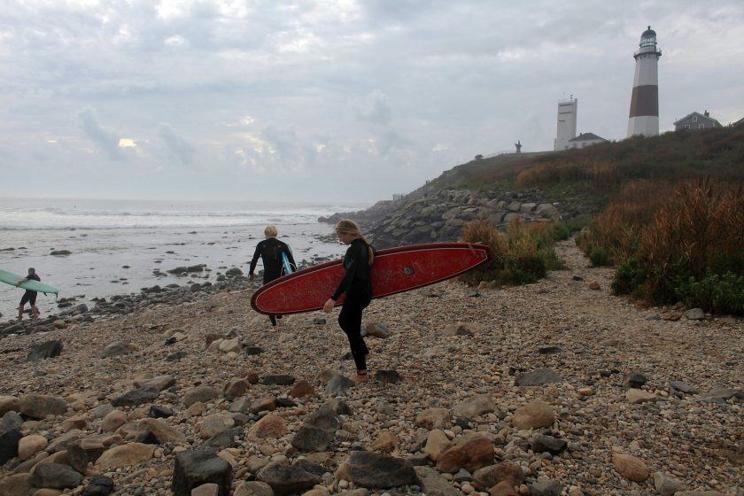 Surfers head out to the water at the Montauk lighthouse on September 3, 2010 in Montauk, New York