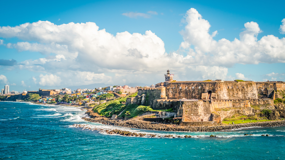 Colorful image with fortification Castillo San Felipe del Morro along the coastline in San Juan, Puerto Rico. Blue sky and white clouds.