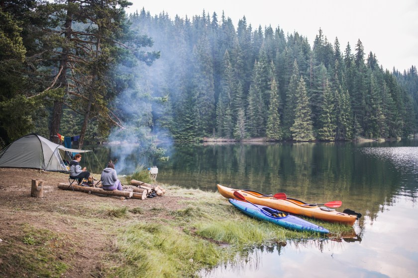 A shot of two beautiful woman having good time in a wild camping near to lake.