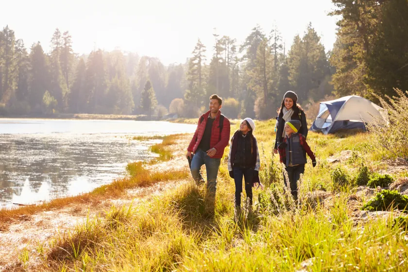 Parents and two children on camping trip walking near a lake