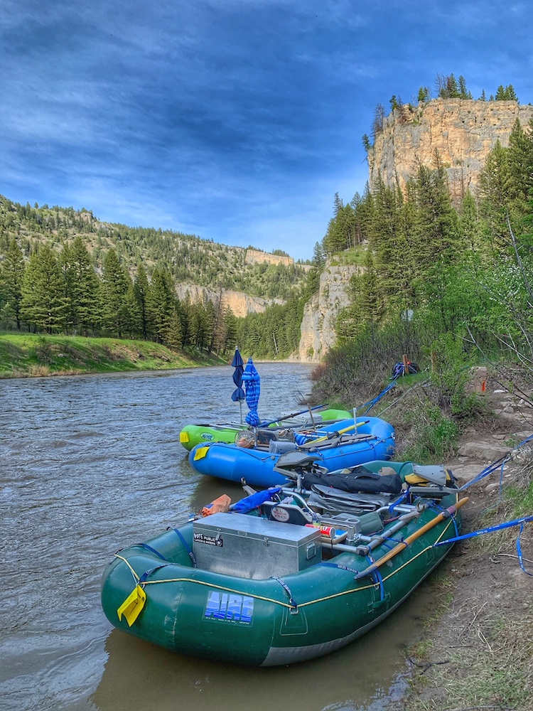 two rafts moored to shoreline in foreground as river winds through valley in background