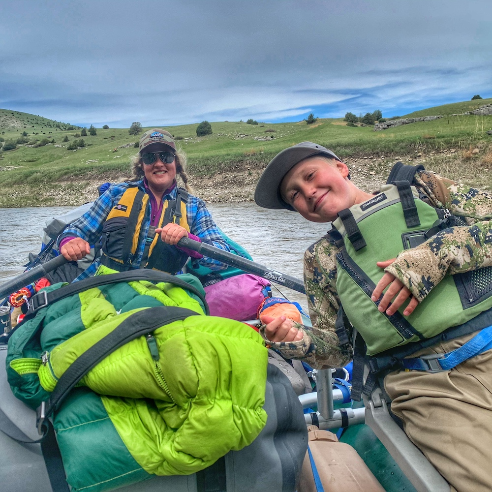 woman and young boy smile for camera while rafting