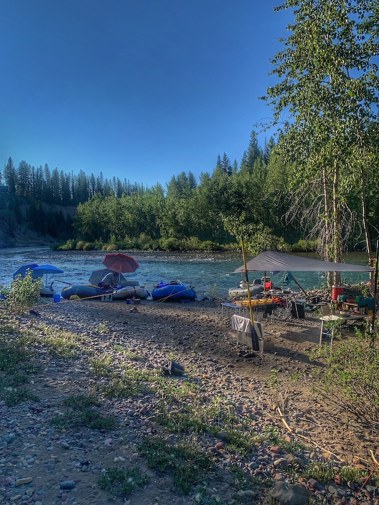 three rafts are moored to a shoreline next to a campsite