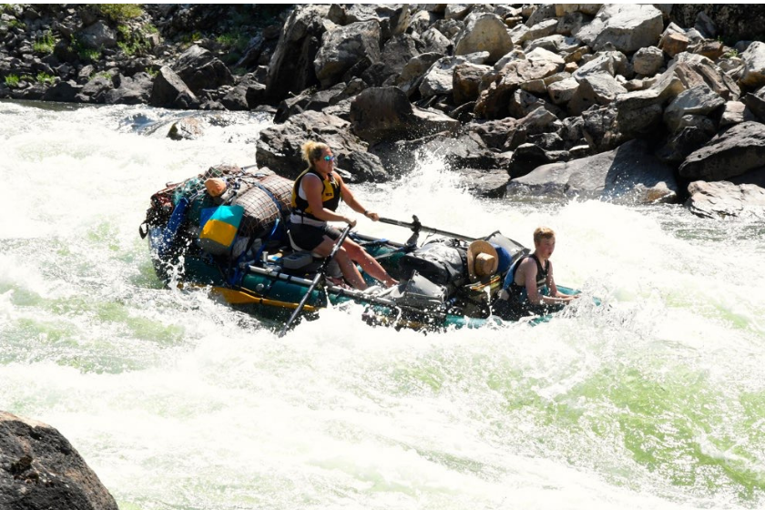 woman and young boy rafting down whitewater rapids