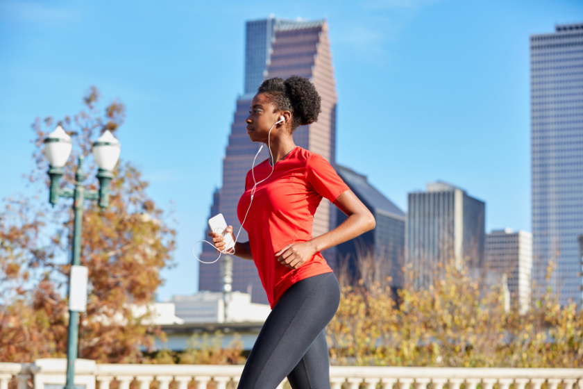 Runner girl running and listening music earphones in the city park