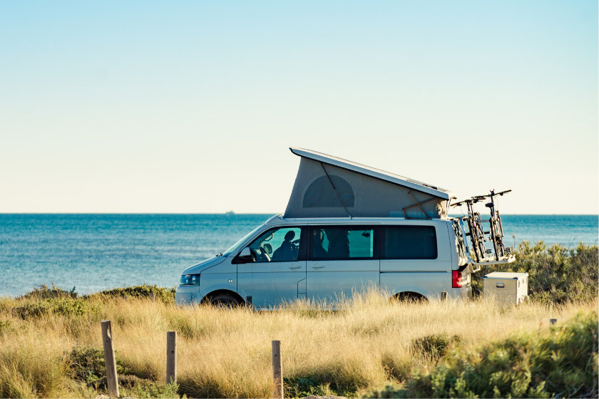Camper van with roof top tent camping on mediterranean sea coast. Holidays and travel in motorhome.