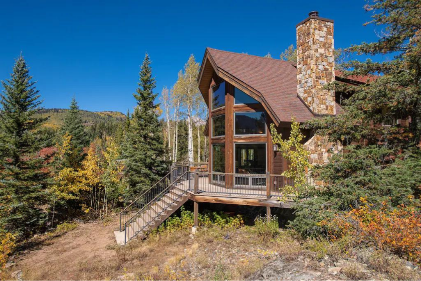 view of a large cabin on a hill with mountains in background