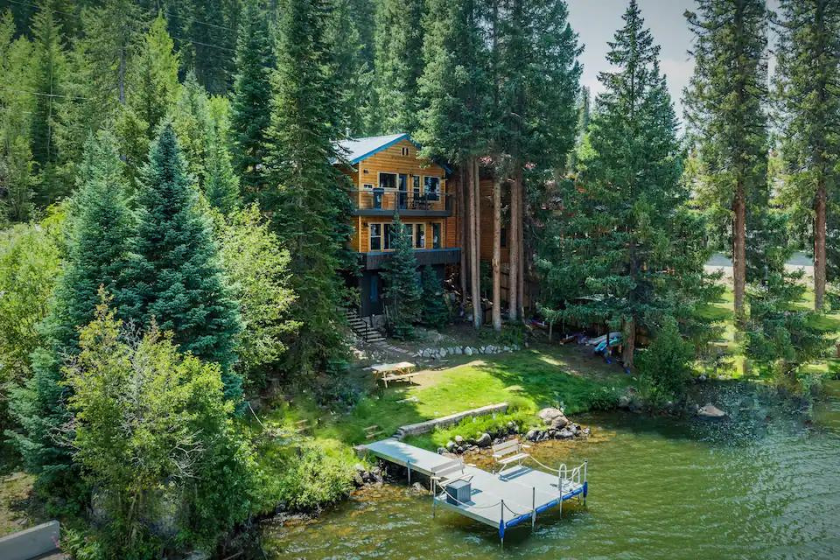 a cabin rests in the woods near a lake