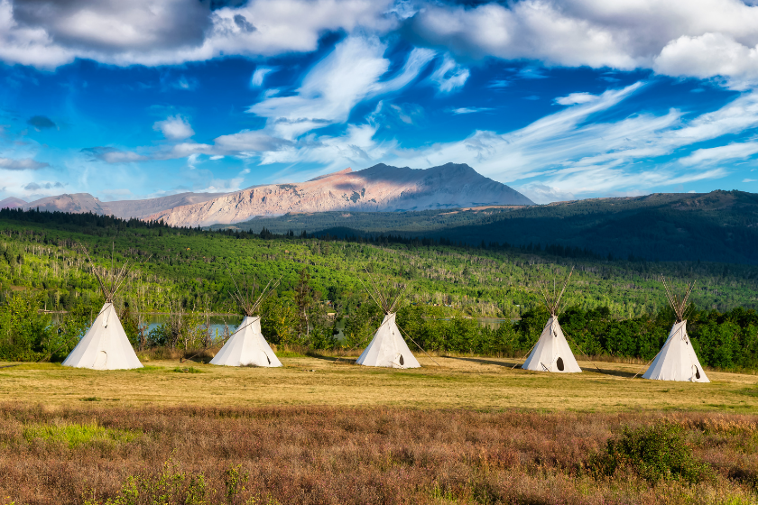 Beautiful View of the Tipi in a field with American Rocky Mountain Landscape in the background. Colorful Sunny Morning Sky. Taken in Montana near Glacier National Park, USA.