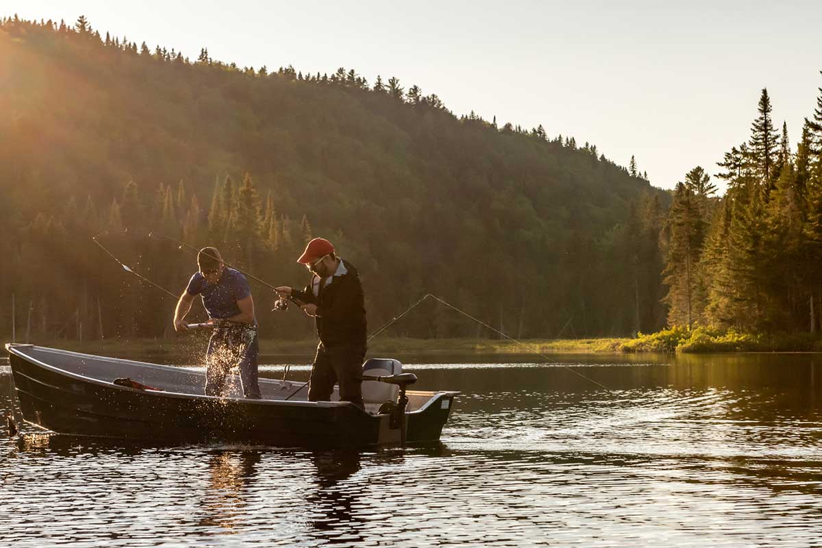 Two anglers fish in a lake from a fishing boat.