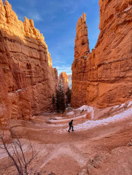 a hiker hikes between two tall canyon walls in the snow of winter