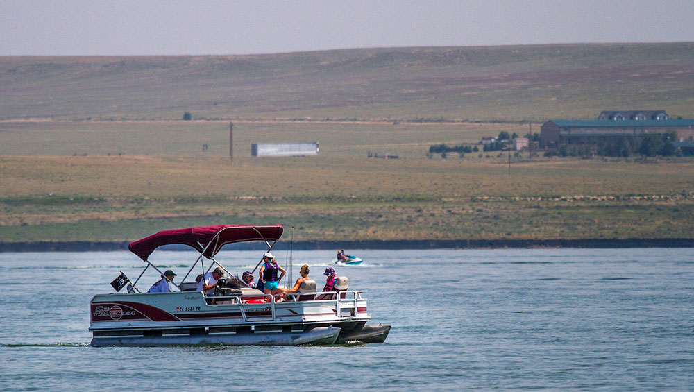 a boat full of people on jackson lake in colorado. the plains in background indicate why it's one of the best lakes for stargazing