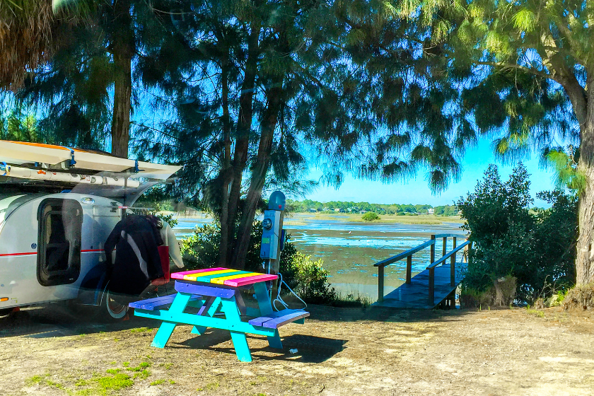 rv and picnic table under foliage near a florida lake