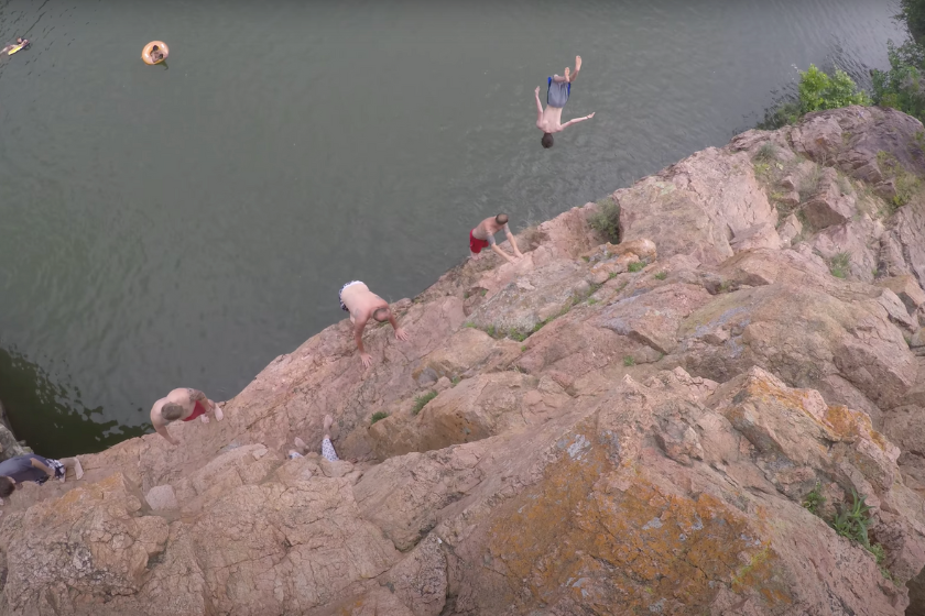 a young man backflips off a cliff
