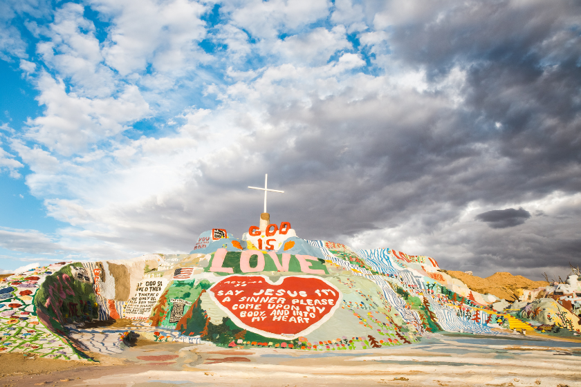 Colorful Salvation Mountain under a cloudy sky in California desert