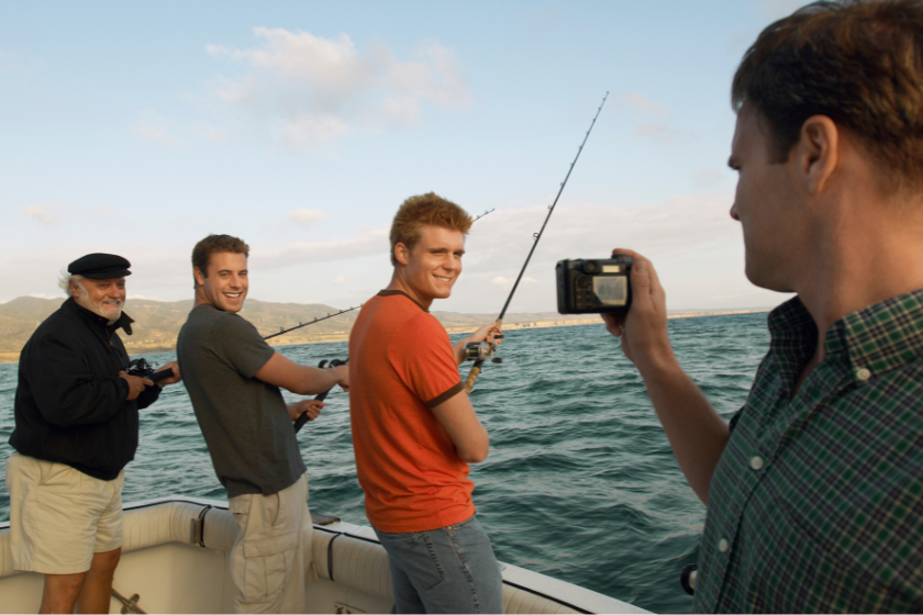 family sport fishing. one of them, in foreground, is taking a picture with a camera