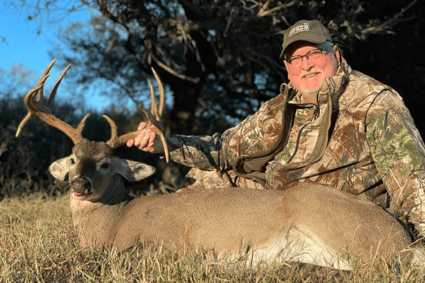 a man with a beard poses with a dead deer