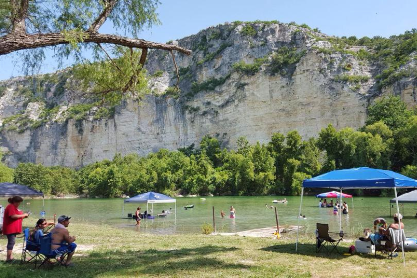visitors enjoy the swim hole in front of a giant chalk bluff